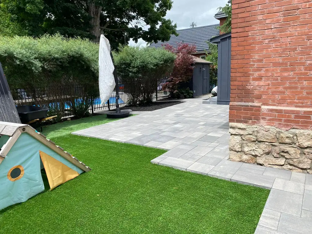 Artificial turf lawn beside a new paver patio