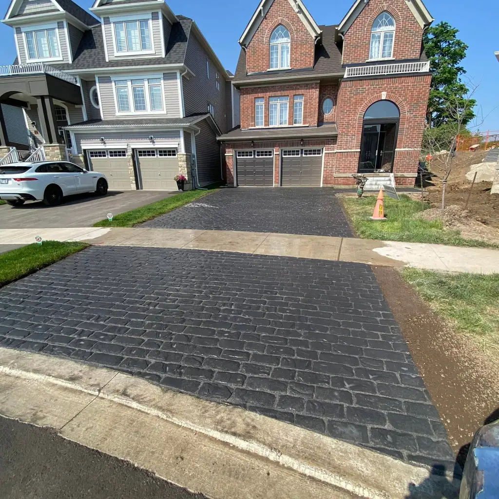 Dark interlock driveway in front of a brick home