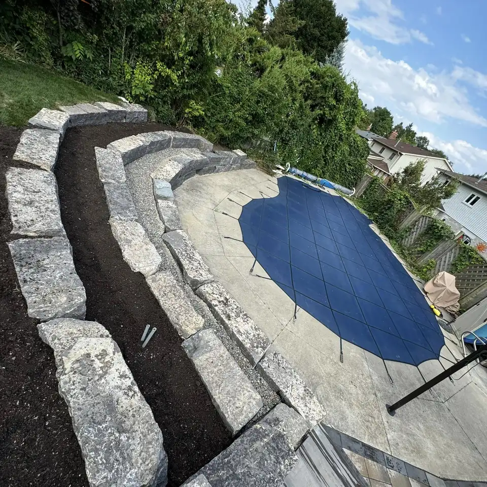 Armour stone retaining wall terraced around a pool