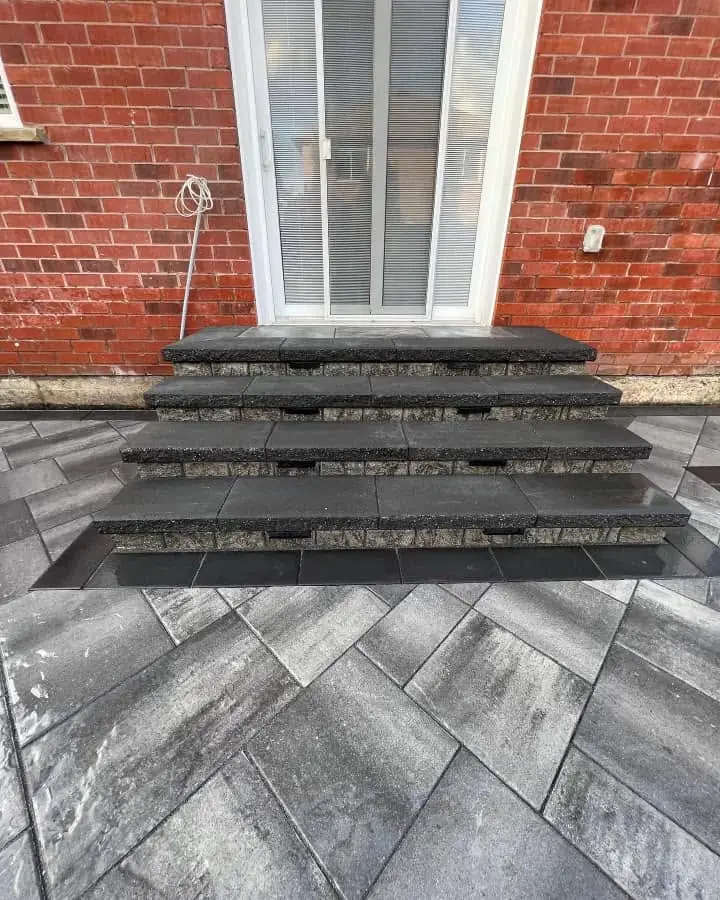 New charcoal stone steps onto a herringbone paver patio